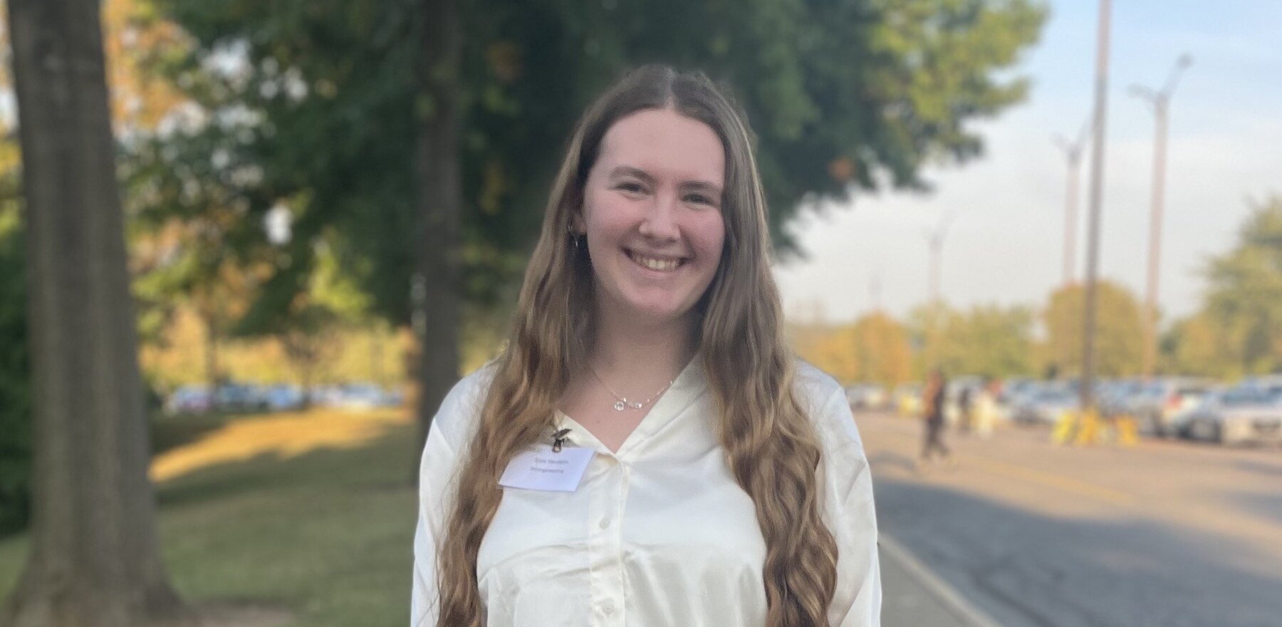 A young woman standing on a sidewalk and smiling for the camera