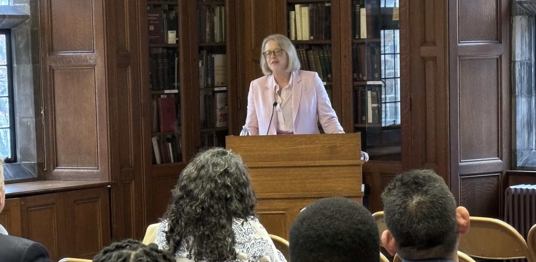 Karin Fischer speaking at a podium to a crowd