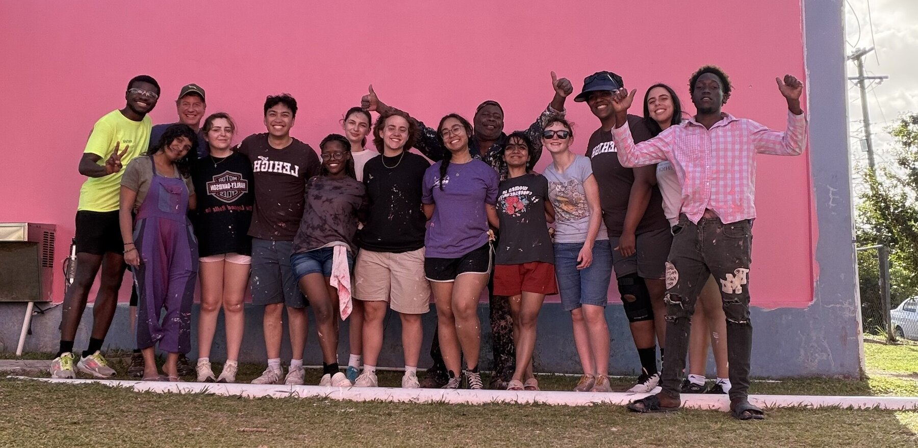 A group of people posing in front of a pink wall