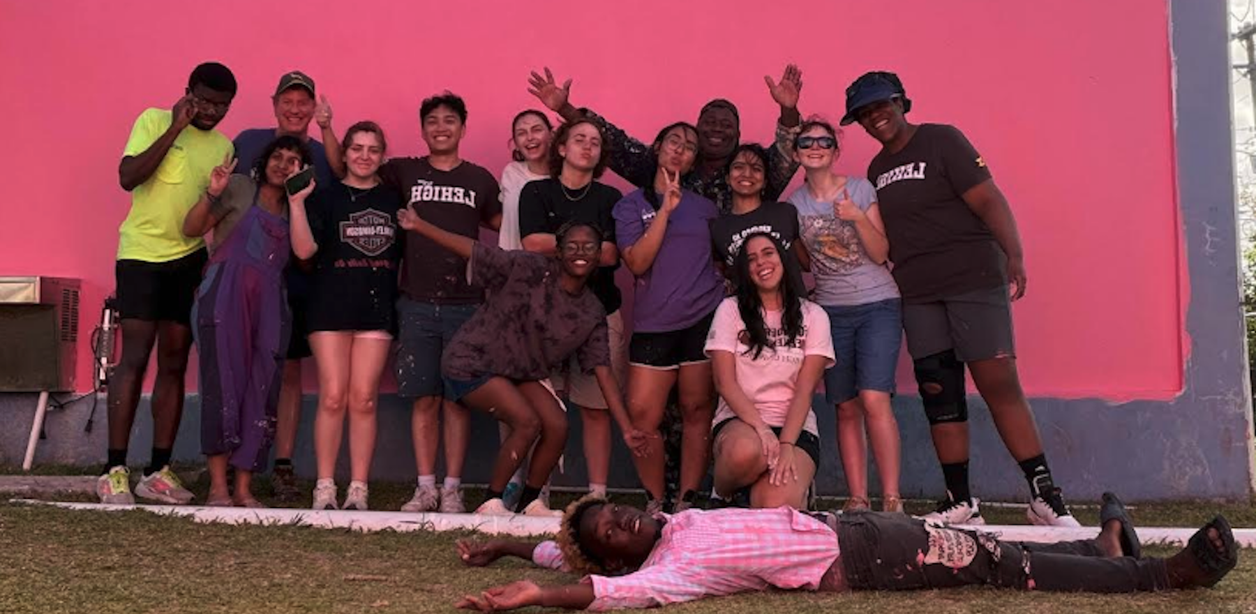 A group of people posing in front of a pink wall