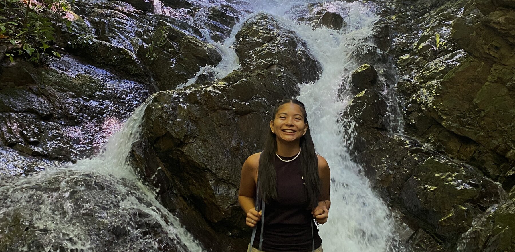 A young woman standing in front of a waterfall
