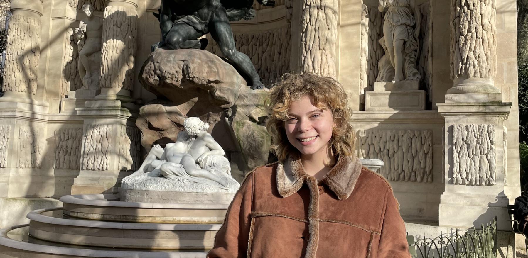 Liana Secondino standing in front of a statue in Paris and smiling for the camera