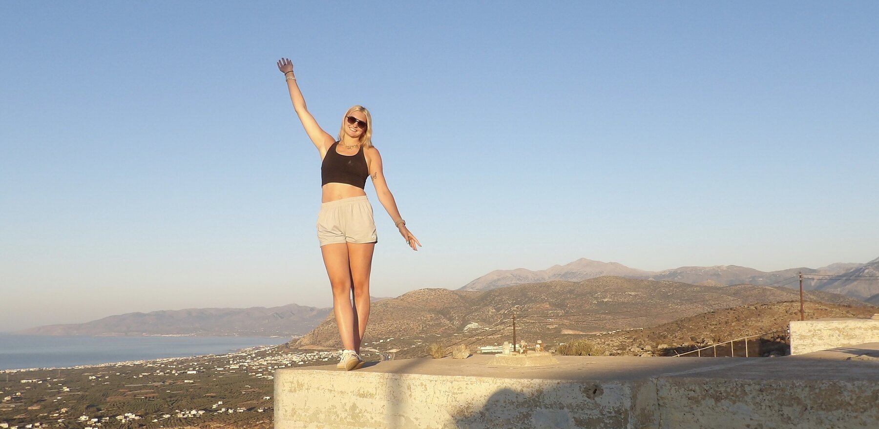 A college student standing near the edge of a cliff in Greece
