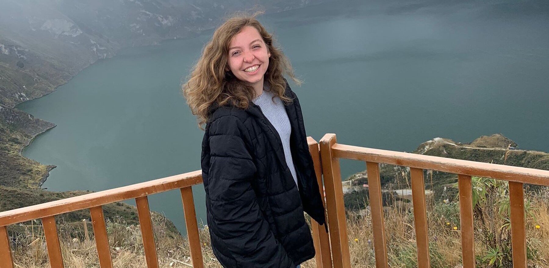 Liz Matthews standing on a wooden deck with an lake view behind her