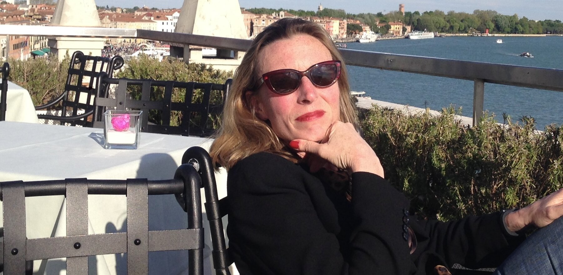 Penny Frohling wearing sunglasses and sitting at an outdoor dining table