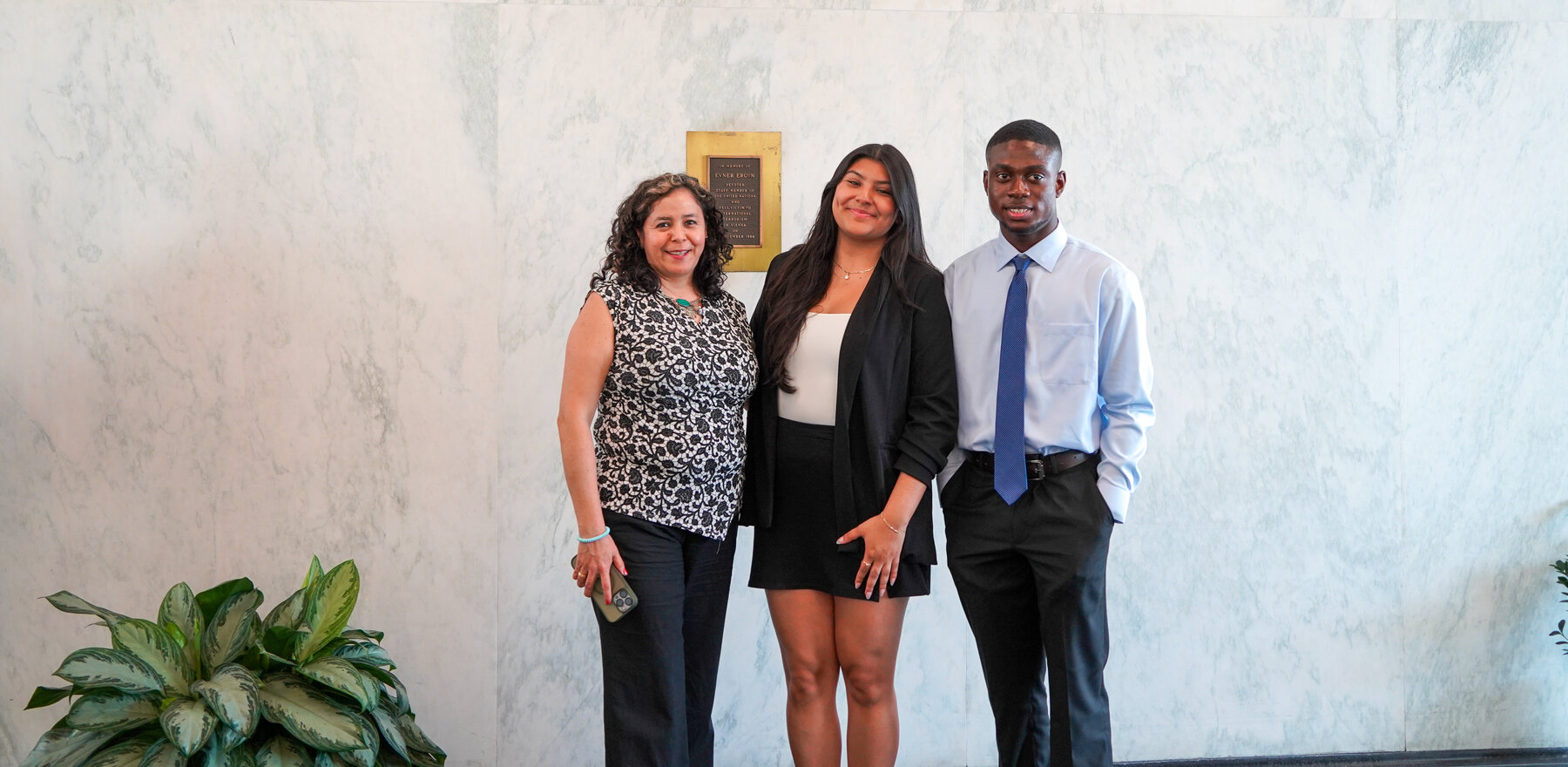 Three people posing for a photo in front of a marble wall