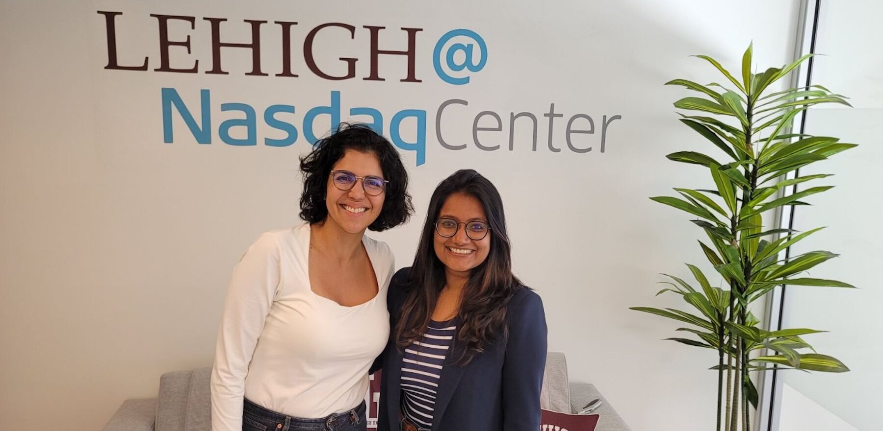 Two women stand in front of a Lehigh@NasdaqCenter logo