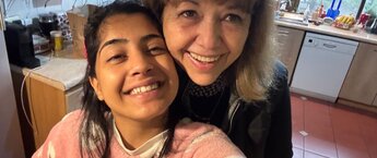 A young woman and older woman in a kitchen smiling for a selfie