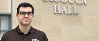 A man in glasses standing in front of a building
