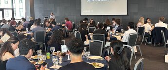 A group of people eating dinner at tables in a large conference room