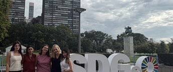 A group of people standing in front of a sign that says SDGs