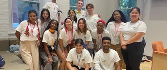A group of students posing for a photo while wearing matching white t-shirts