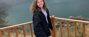 Liz Matthews standing on a wooden deck with an lake view behind her