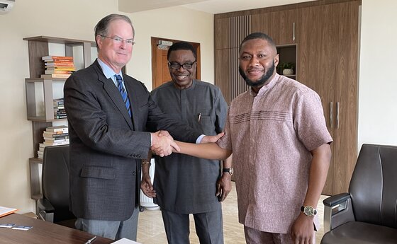 A man shaking hands with another man while they smile for the camera