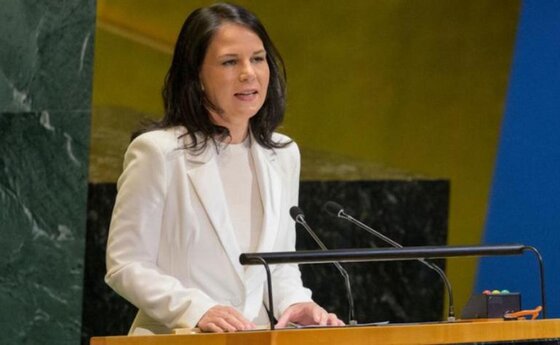 A woman in a white pantsuit speaking at a podium