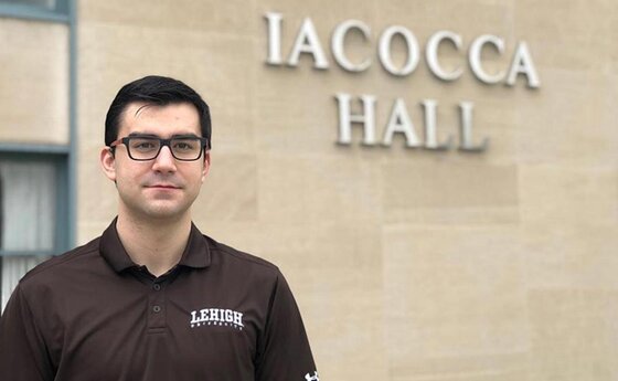 A man in glasses standing in front of a building