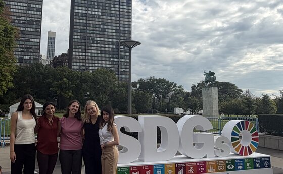 A group of people standing in front of a sign that says SDGs