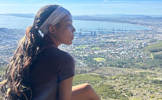 A young woman sitting and looking out at a landscape horizon
