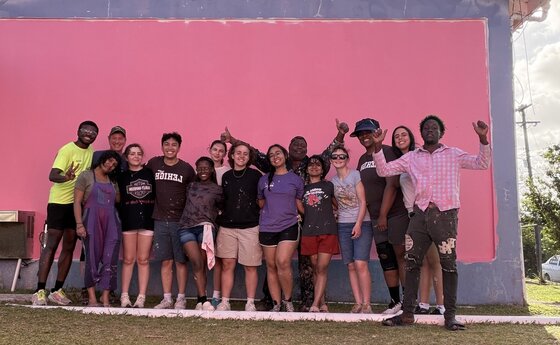 A group of people posing in front of a pink wall