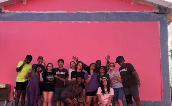 A group of people posing in front of a pink wall