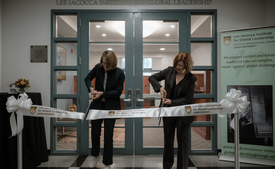 Two women cutting a ribbon at a ribbon-cutting event in an office setting