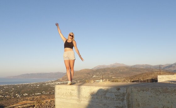 A college student standing near the edge of a cliff in Greece