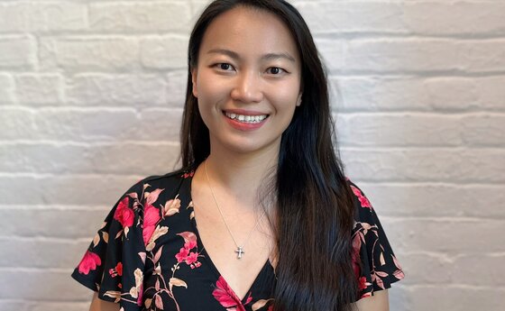 A woman smiling while standing in front of white brick