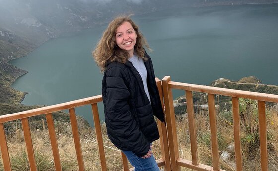 Liz Matthews standing on a wooden deck with an lake view behind her