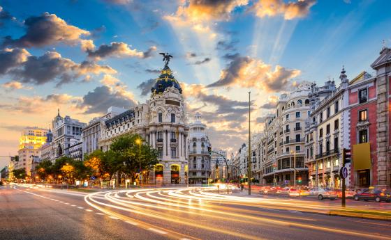 A time-lapse photo of Madrid buildings with the sun setting in the background