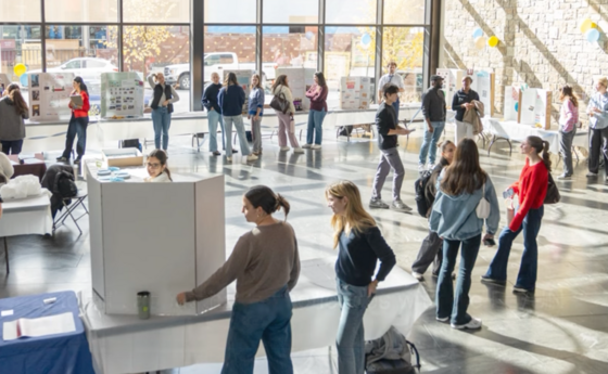 A group of people gathered in a lobby with information tables scattered throughout the room