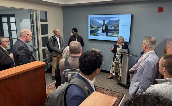 A group of people listening to a woman talk in an office