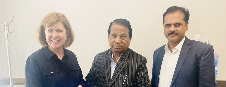 Three people standing together and posing with a blue package