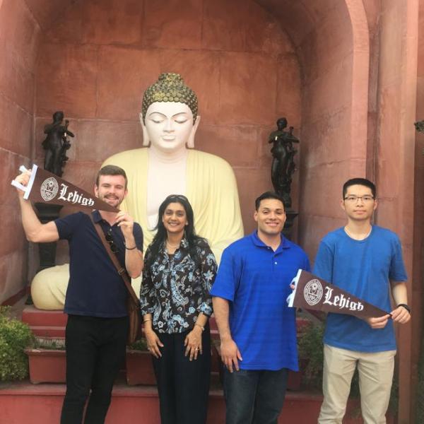 Four people posing for a photo in India while holding up India flags