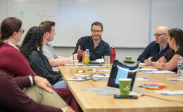 A group of people listening to a man speaking at a table