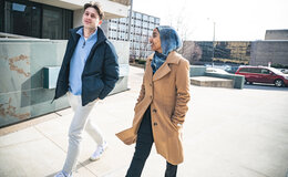 Two people walking in a plaza and talking