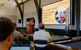 A group of people in seats watching a Powerpoint presentation