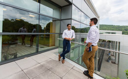 Two people standing outside the glass windows of a building