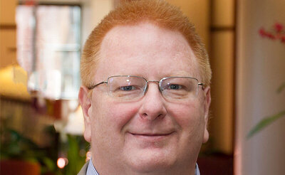 joe perfetti in a tan suit and blue shirt