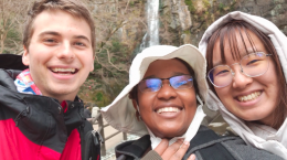 Three young people smiling for the camera with a waterfall behind them